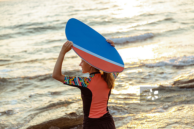 年轻的白人女性手持滑板看着大海图片素材