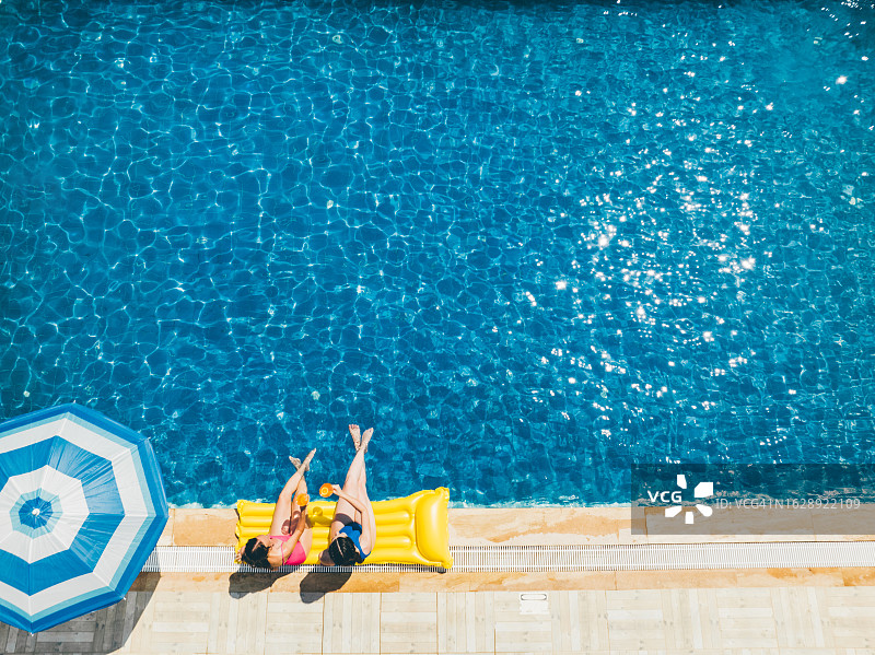 阳光明媚的日子里，女朋友们在泳池边享受饮品图片素材