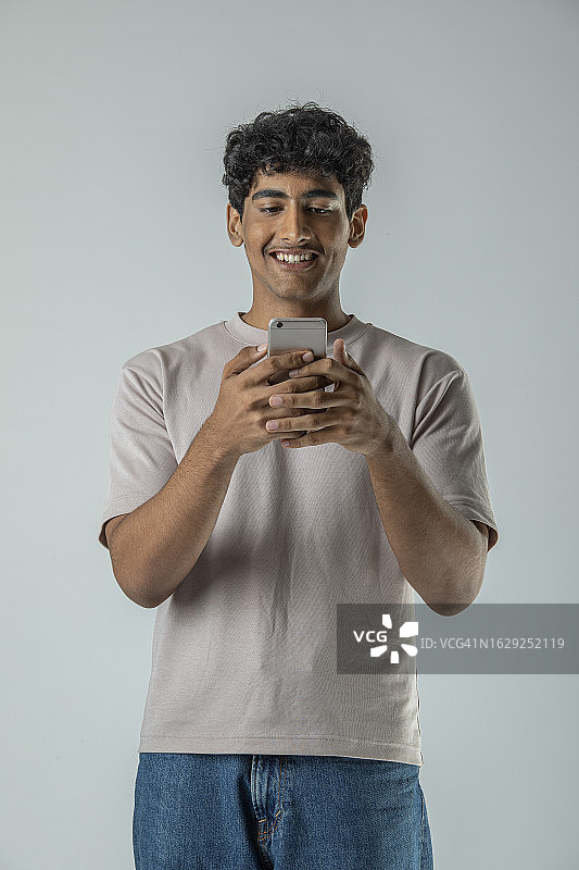 在白色背景上用智能手机发信息的青少年男孩图片素材