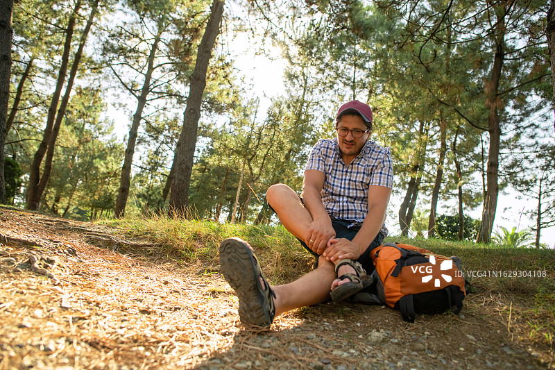 男子在森林或公园里行走时脚踝疼痛图片素材