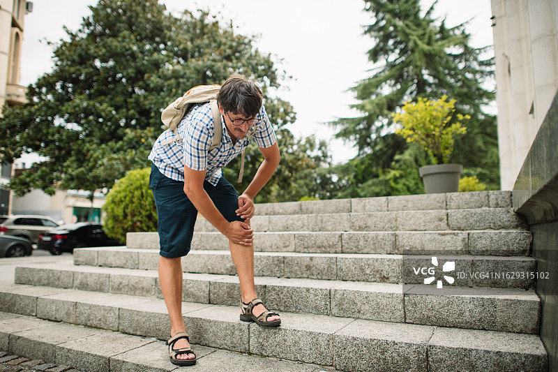 在夏日城市街道上膝盖疼痛的男人图片素材