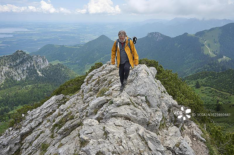 徒步旅行者：65岁老年人在德国上巴伐利亚基姆高阿绍坎彭万峰顶山脊上图片素材
