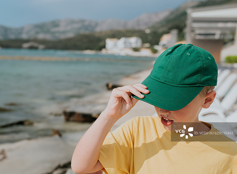 小男孩摸着绿色帽子的顶部图片素材