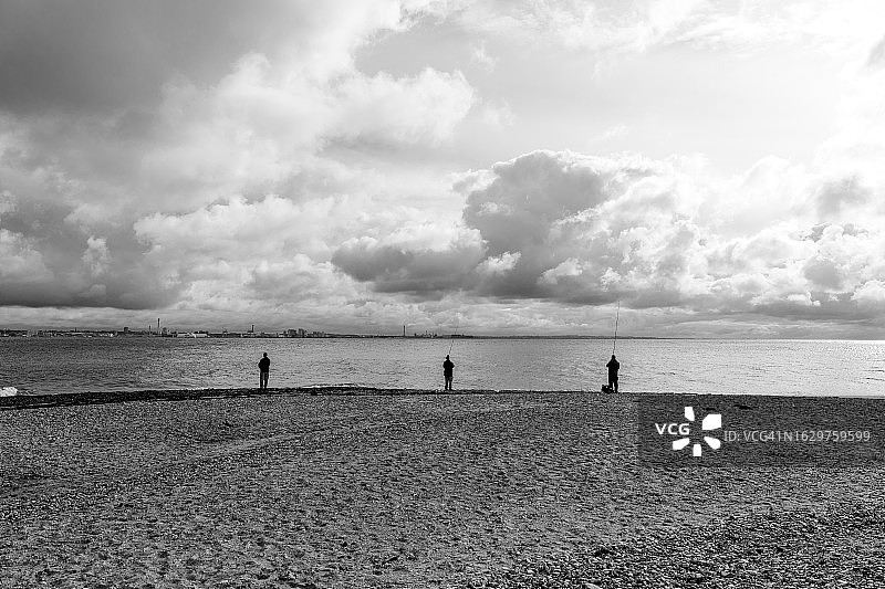 三名男子在阴天背景下钓鱼图片素材