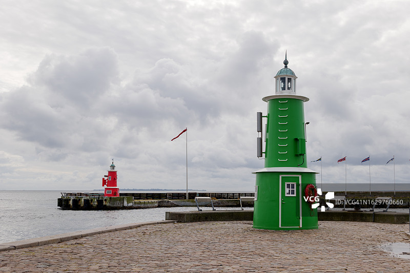 阴天背景下，岸边的绿色灯塔图片素材