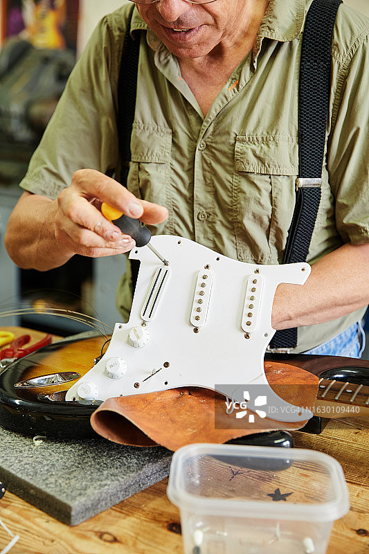 工匠在工作室修理电吉他的竖版照片图片素材