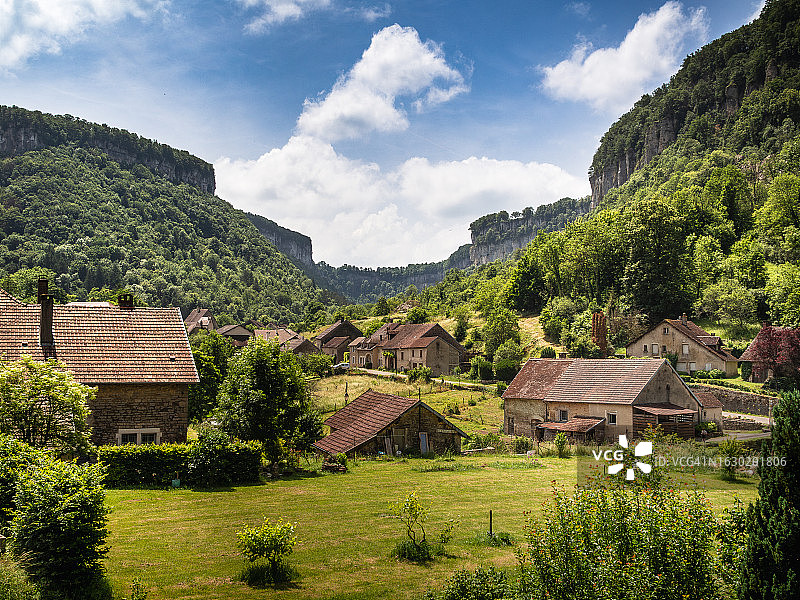 法国东部汝拉Baume-les-Messieurs陡峭峡谷的广角视图，石灰岩悬崖环绕着城镇图片素材