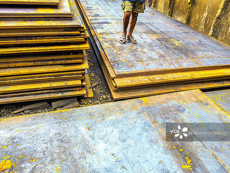 在印度孟买的钢铁供应商的院子里，一名工人（身份不明）在出售给客户之前，根据批次对钢板进行分类图片素材