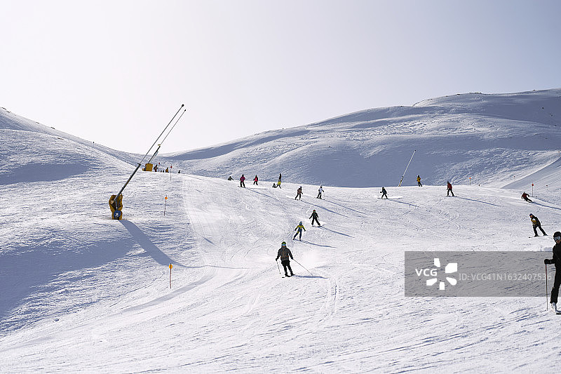 阳光明媚的冬日，一群人在山上滑雪的正面图图片素材