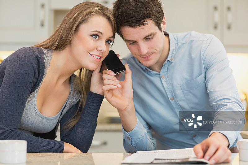 男人拿着智能手机在女人耳边图片素材