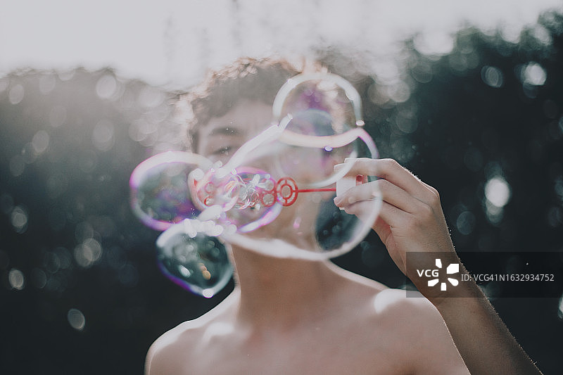 男人吹泡泡棒，吹出泡泡漂浮在他周围的空中图片素材