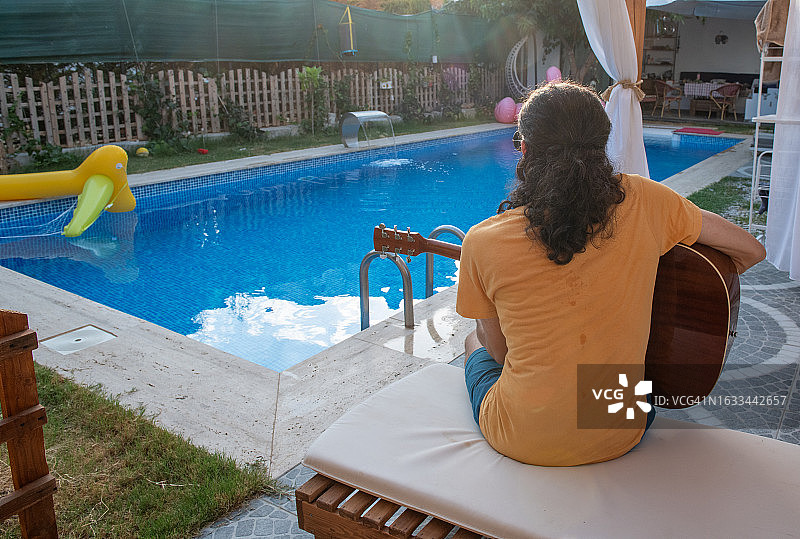 年轻音乐家在泳池里弹吉他图片素材