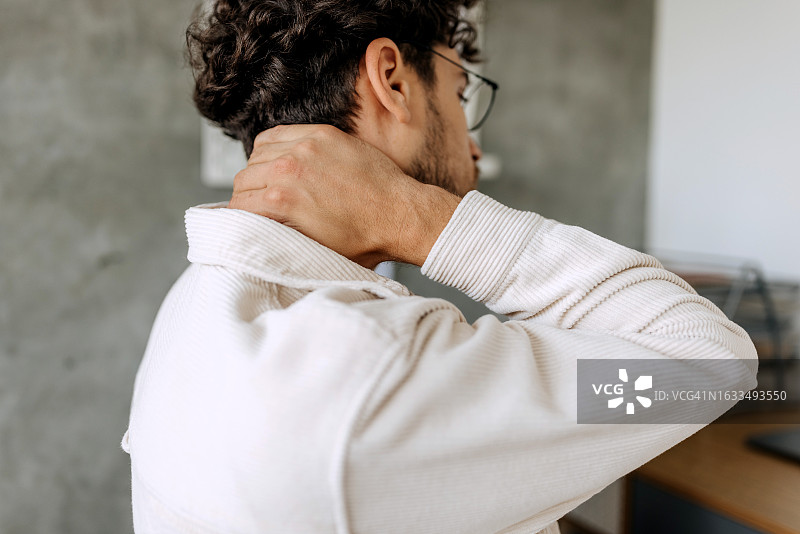 年轻男子在家办公时颈部疼痛的特写镜头图片素材