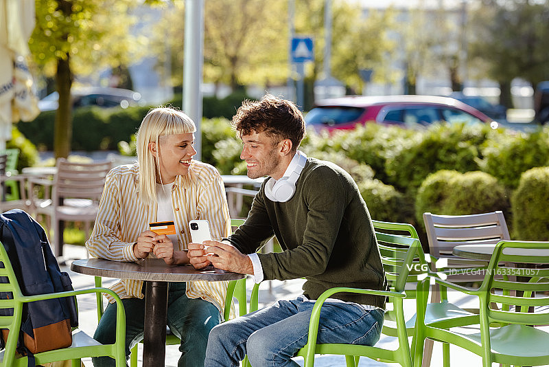 年轻人在户外使用智能手机和信用卡图片素材