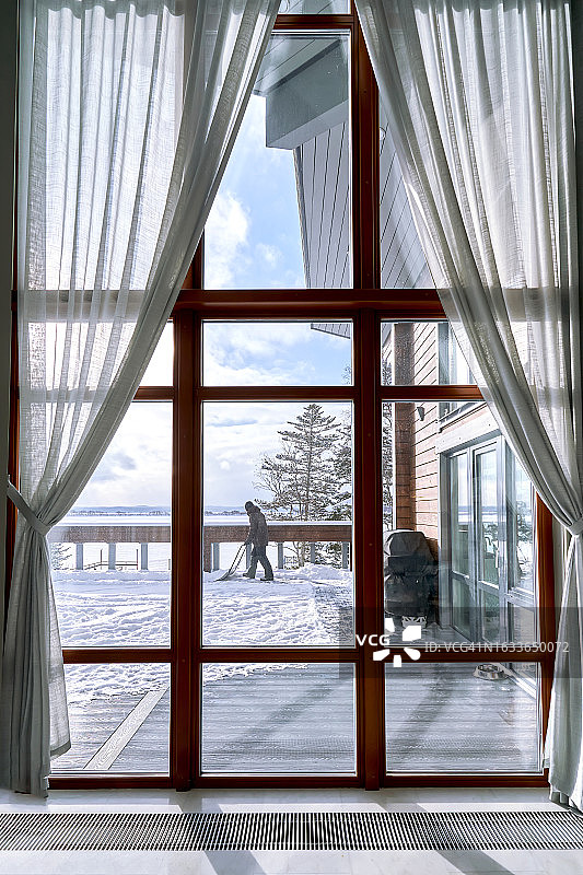 男人清理乡间别墅窗外的积雪图片素材