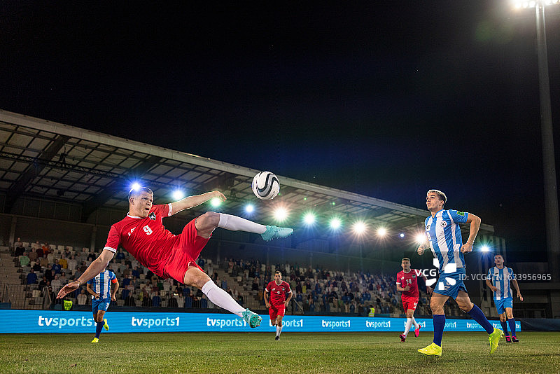 年轻男子在半空中踢足球图片素材