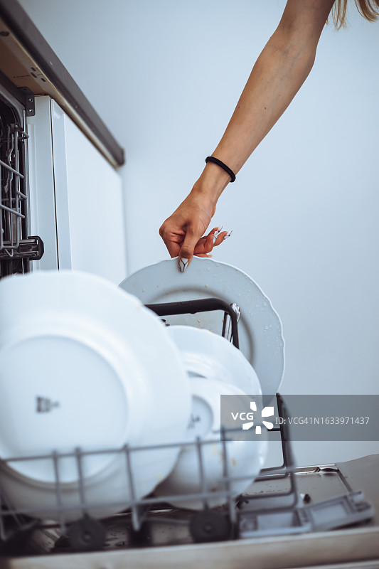少女将白色盘子放入洗碗机图片素材