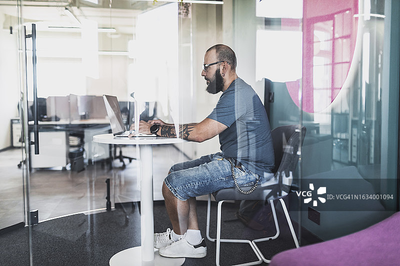 成年男人在创意共享办公室内用笔记本电脑编程图片素材
