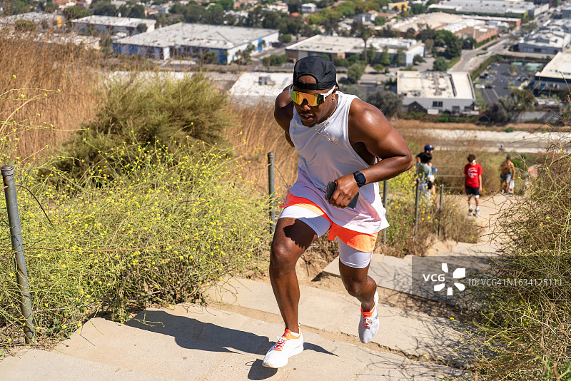 体能教练在晴天户外训练时跑步上山图片素材