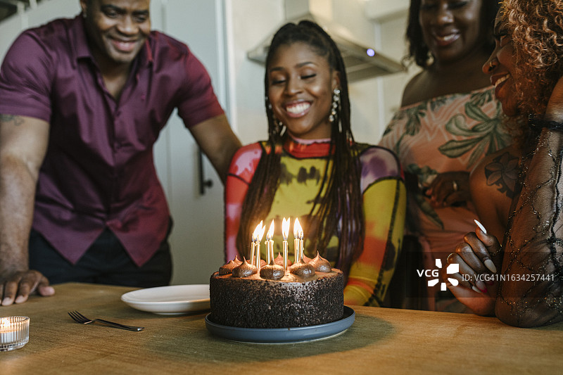 晚宴上，女人面带微笑看着生日蛋糕图片素材