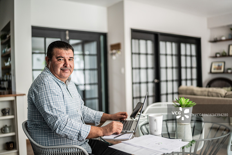 在家使用笔记本电脑工作的成熟男人肖像图片素材