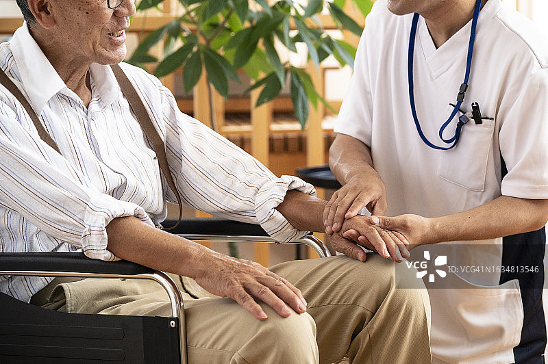 坐在轮椅上与医护人员聊天的年长男人图片素材