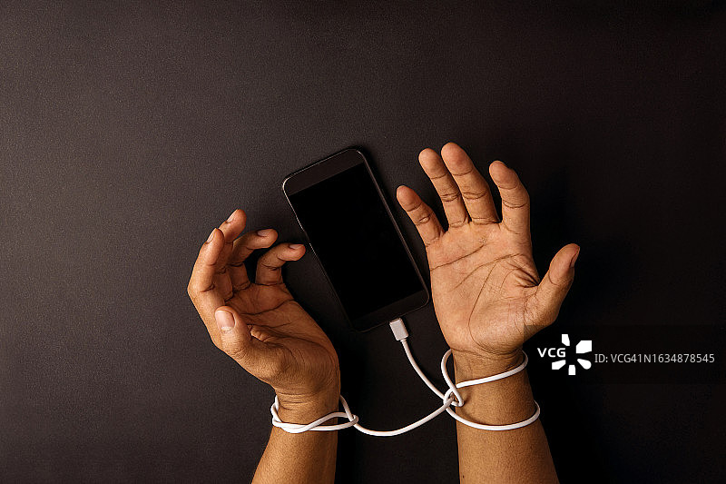 被电话线束缚的手：移动技术概念图片素材