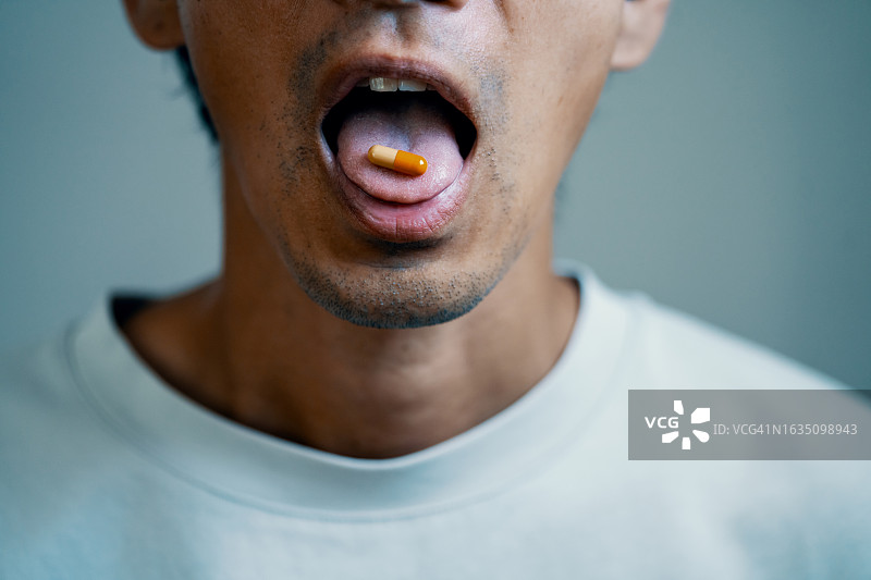 中年男人舌头上的药丸特写图片素材