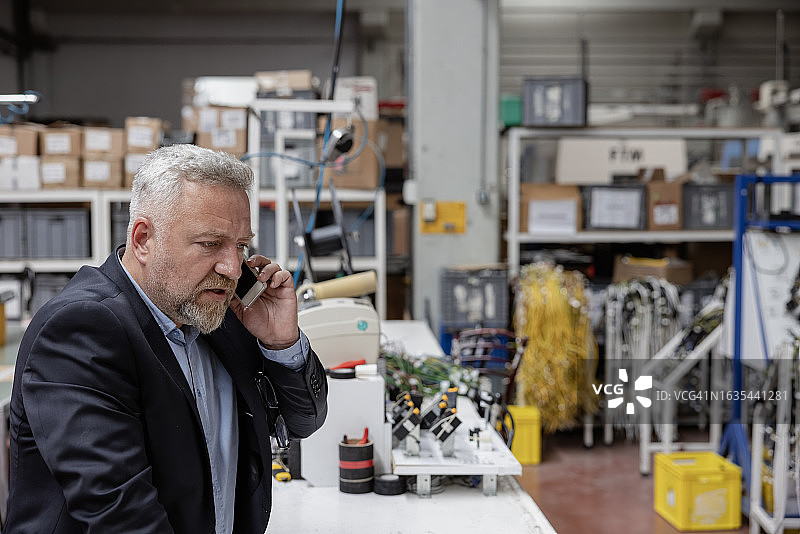 在工厂里打电话的英俊商人图片素材
