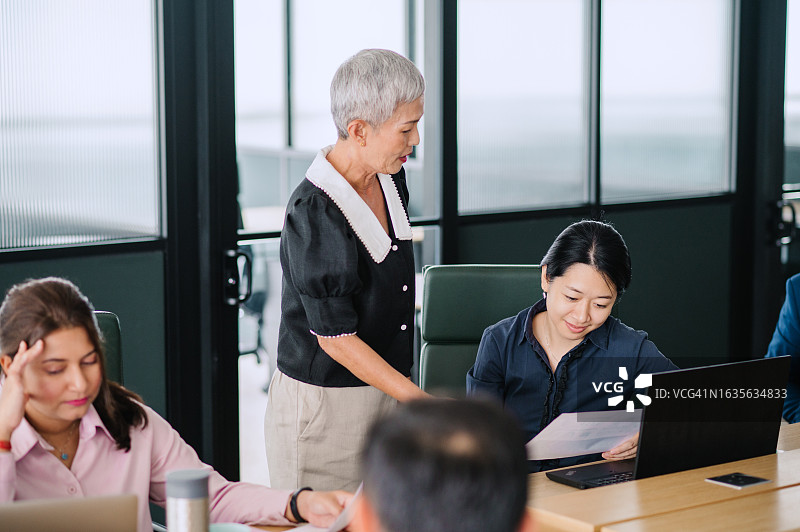 正在指导同事的亚洲资深中国女商人图片素材