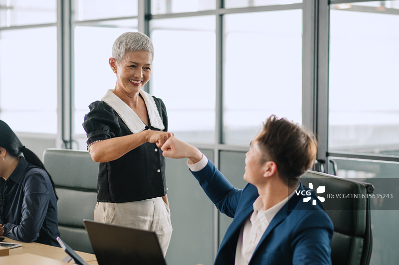 庆祝的亚洲老年妇女和她的同事图片素材