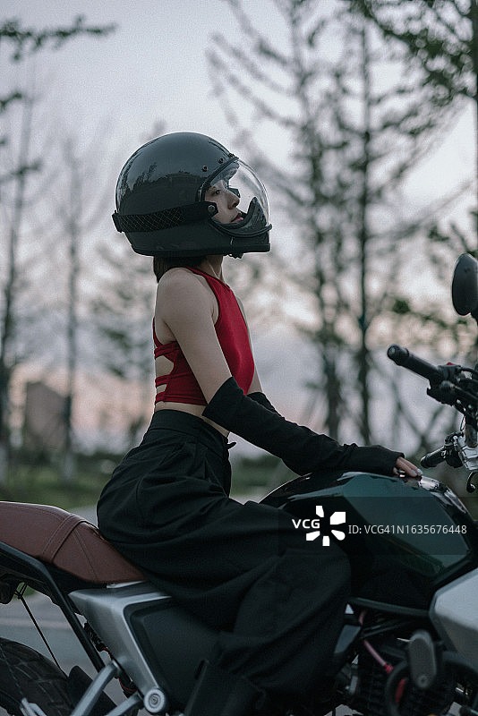 穿着红色衣服的亚洲女人骑着摩托车图片素材