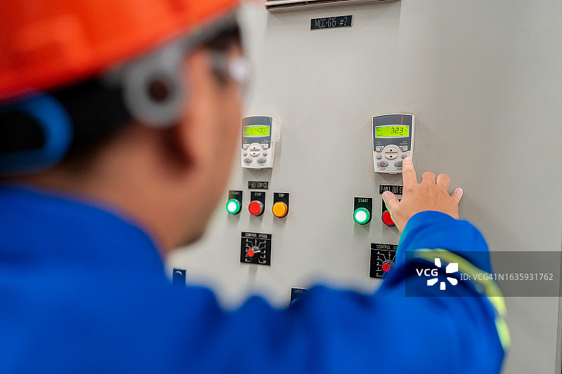 身穿安全制服的技师在制造环境中监测和检查开关柜内电气柜的温度图片素材