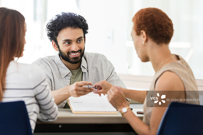 中年妇女签署账户文件后将笔还给银行职员图片素材