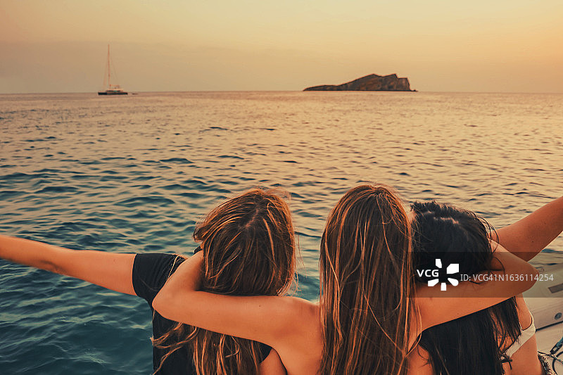 快乐的女性朋友在伊比沙岛日落时分航行欣赏美景图片素材