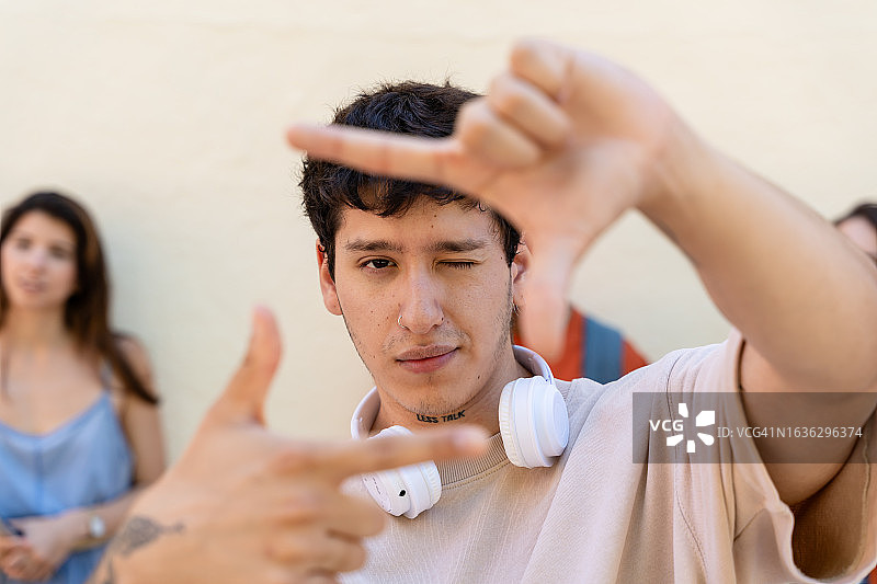 戴耳机和朋友在背景中的年轻男人肖像图片素材