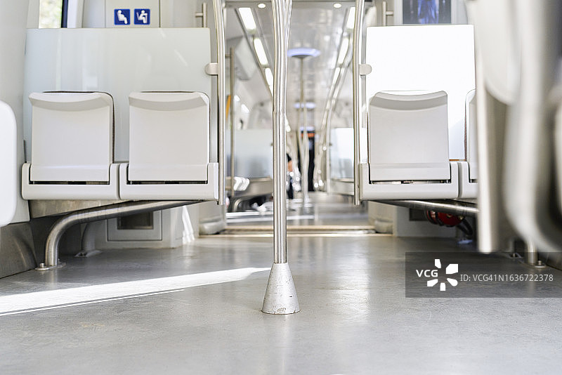 几乎空无一人的地铁内部，有座位、垂直金属杆、信息图像，阳光透过窗户照亮一切。图片素材