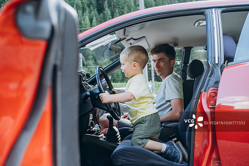 父子开车，儿子握着方向盘，父亲讲解汽车图片素材