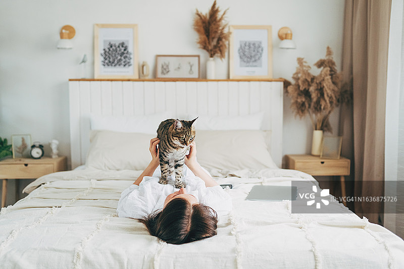 女人和她的猫躺在床上，与动物的友谊图片素材