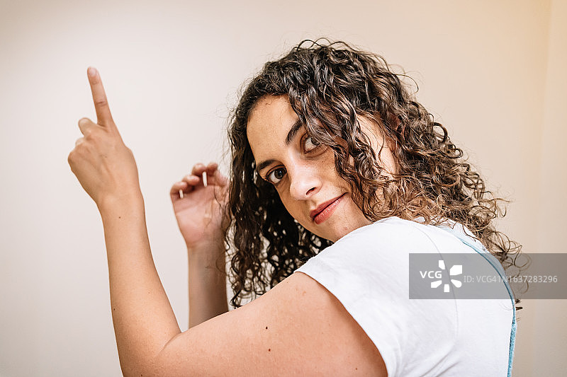 年轻女人指向上方并看向镜头图片素材