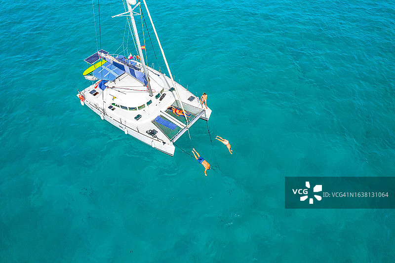西班牙福门特拉岛帆船度假时，朋友们从双体船上跳下的航拍图片素材