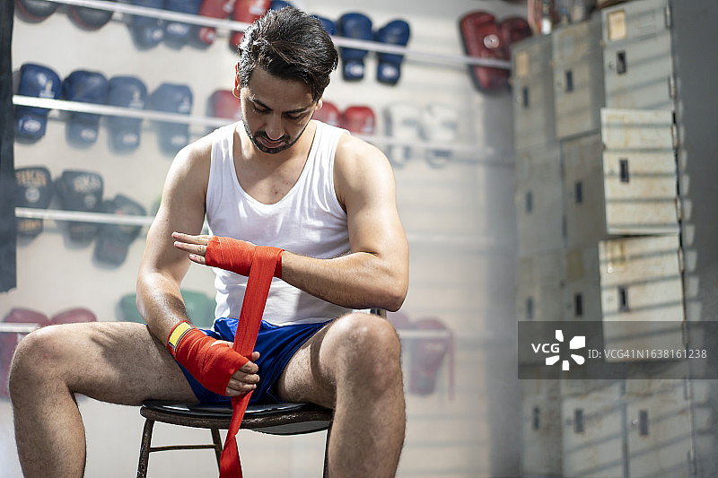 男拳击手在健身房缠绕红色拳击绷带的中段照片图片素材