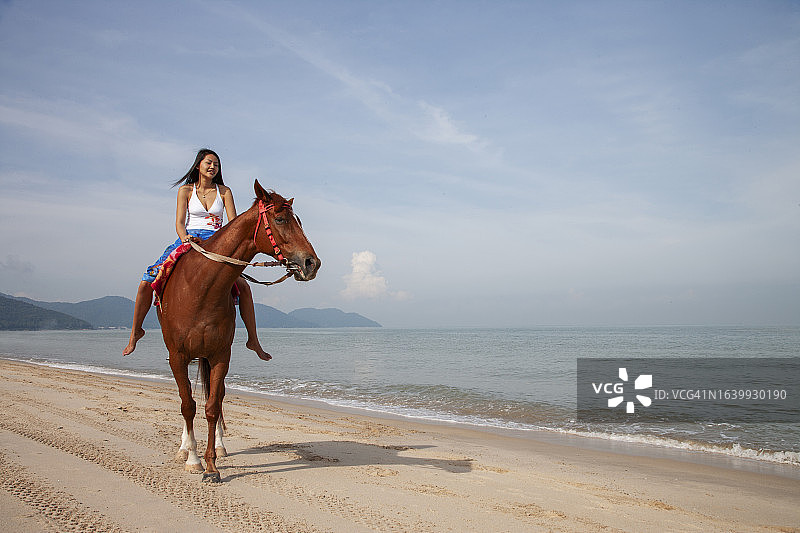 女人在热带海滩上骑马图片素材