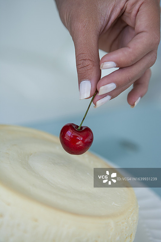 女人在蛋糕上放樱桃图片素材