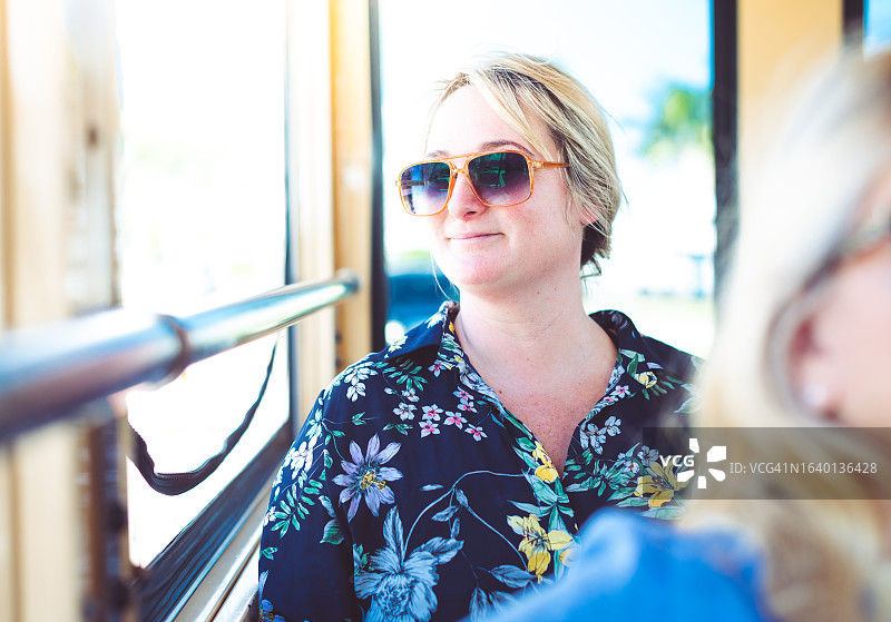戴太阳镜的女人在公共交通工具上向窗外看图片素材