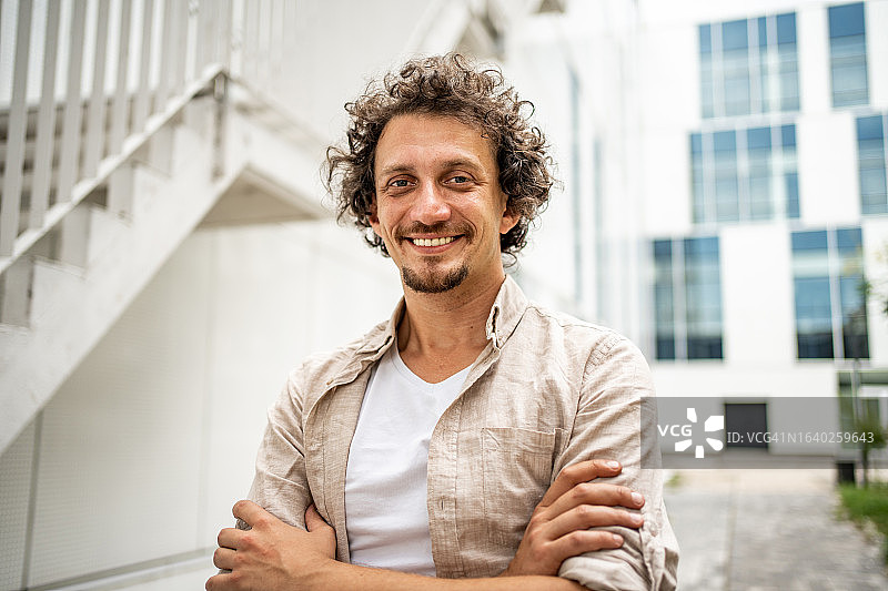 户外站立、双臂交叉并看向镜头的现代中年男人肖像图片素材