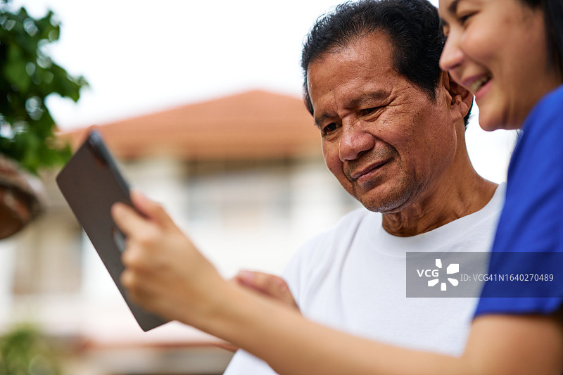 女老师教老年男人在平板电脑上使用社交媒体应用图片素材