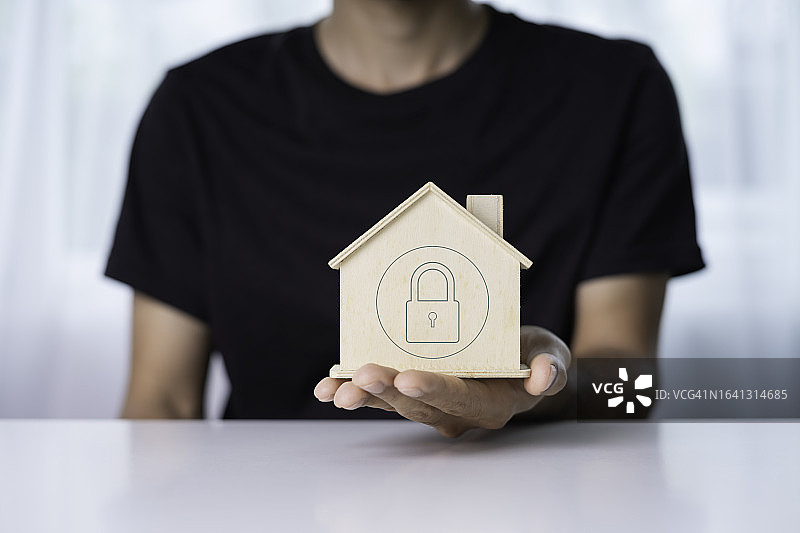 智能家居概念：手持木制房屋模型和自动化安防系统图标图片素材