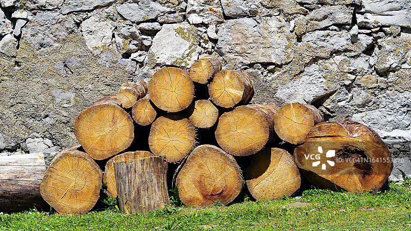 法国埃维昂莱班的草地上和石墙前堆放着一堆木头图片素材