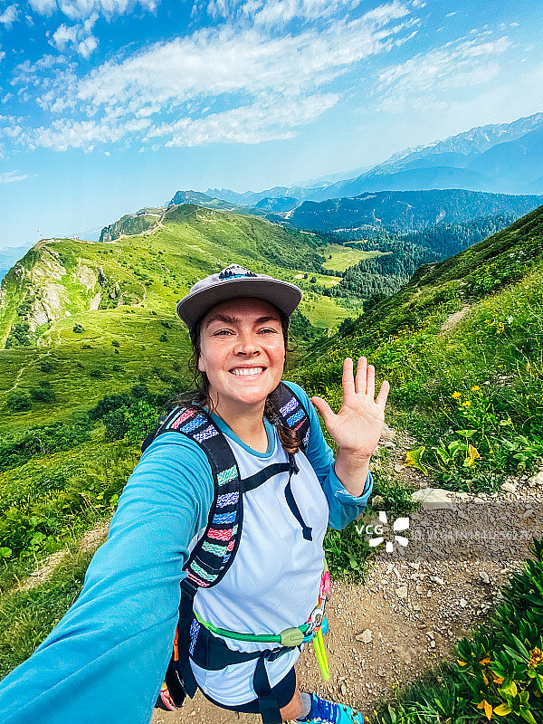 快乐的中年妇女在夏季登山时自拍，欣赏壮丽景色图片素材